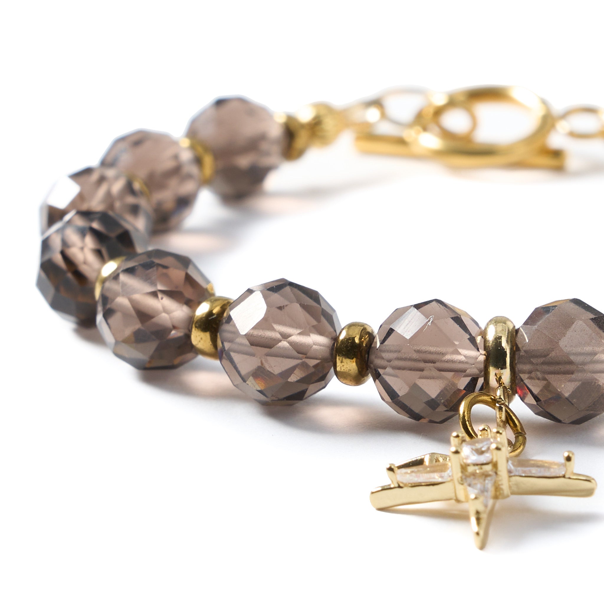 Detailaufnahme eines Armbands aus facettiertem Rauchquarz und Hämatit mit goldfarbenem Anhänger